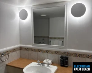 A bathroom mirror surrounded by ambient lighting, featuring a clean sink and minimalistic design